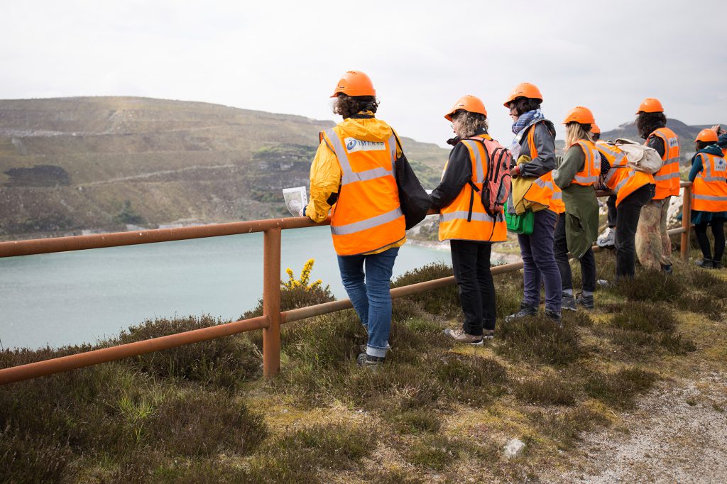 People dressed in high visibility jackets looking into a china clay pit