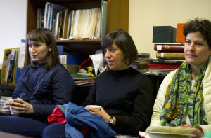 Three women seated on a sofa listening