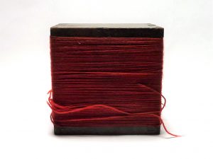 A wooden box, bound in red twine